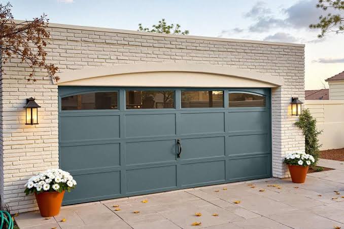 Finished blue-gray garage door set against clean white-painted brick